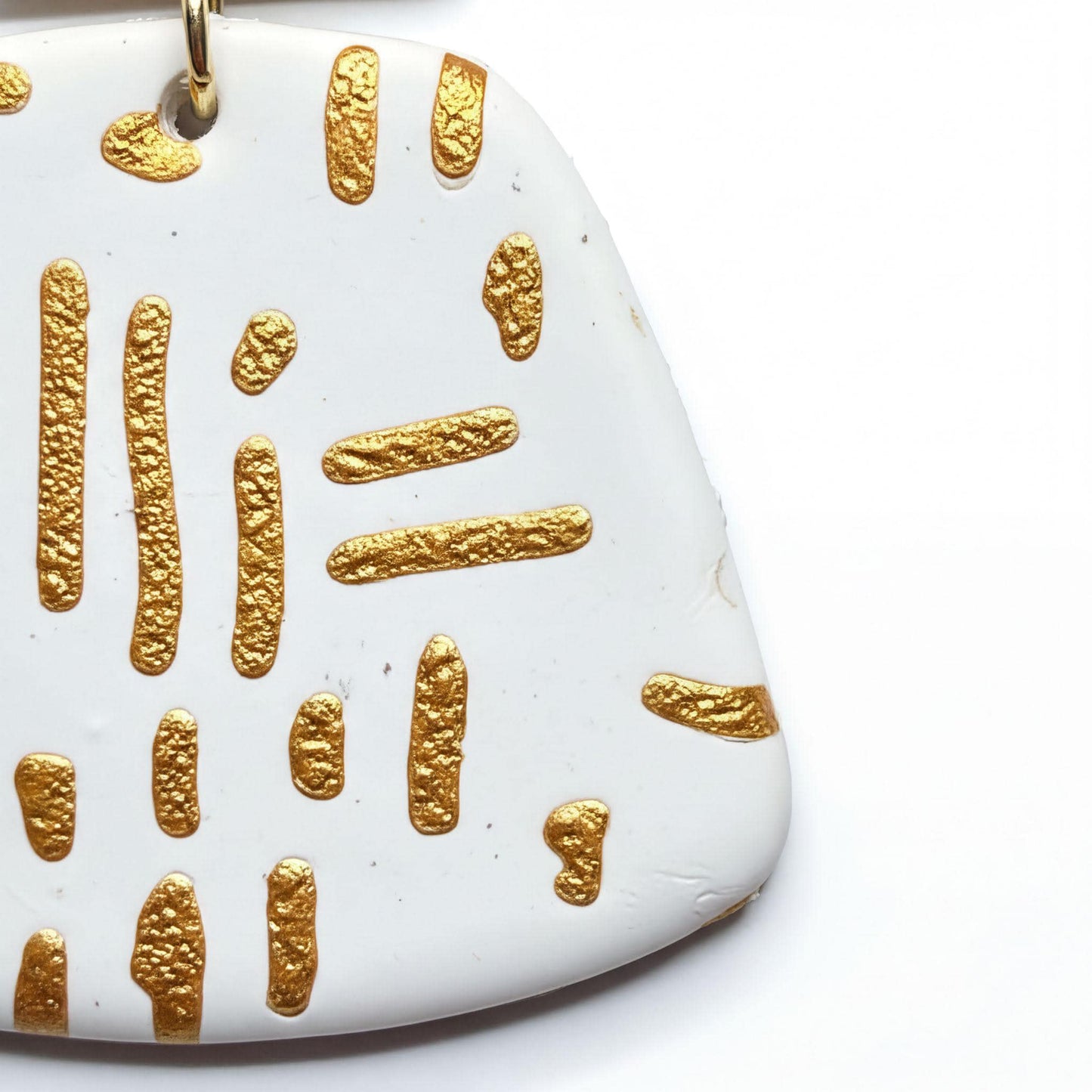 a close-up view of a white ceramic object with a gold-colored design on it.