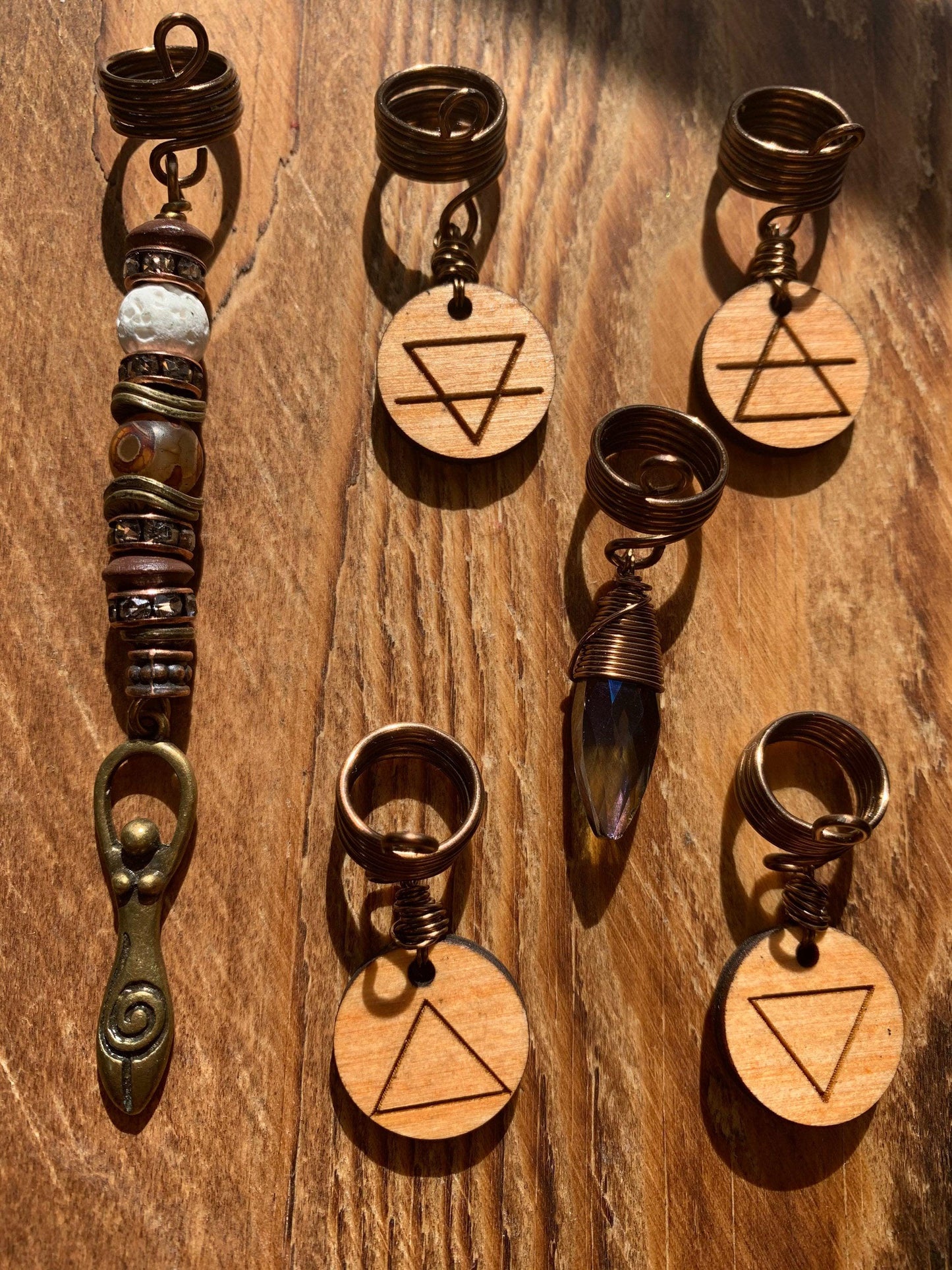 a collection of various wooden charms and pendants, each with unique designs and symbols, arranged on a wooden surface.