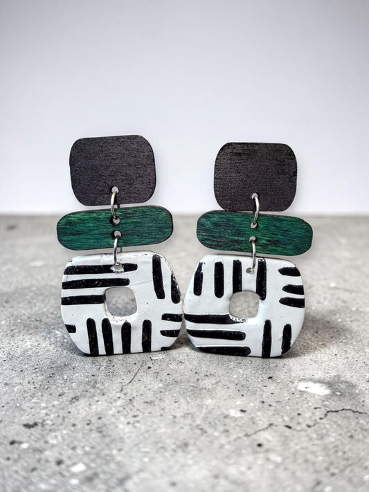 A pair of earrings with a black and white striped design, featuring a combination of green and black elements.