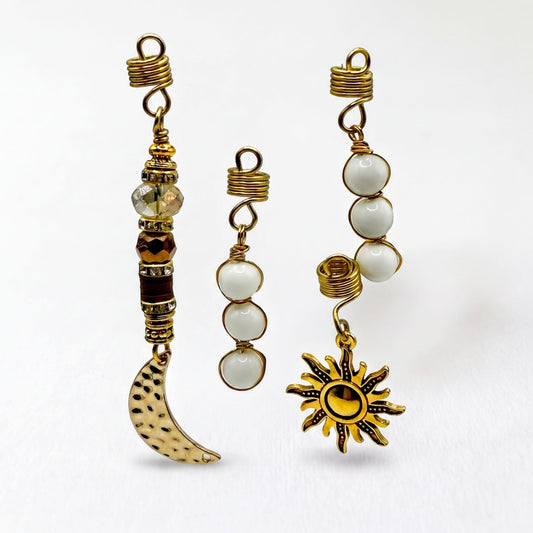 three unique earrings with various designs and materials, including beads, a crescent moon, and a sun-shaped pendant.