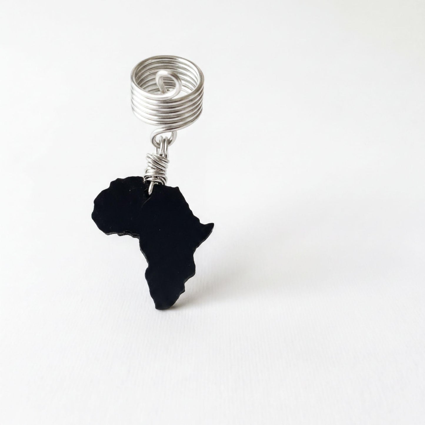 A black silhouette of Africa is suspended from a silver spiral ring on a white background.