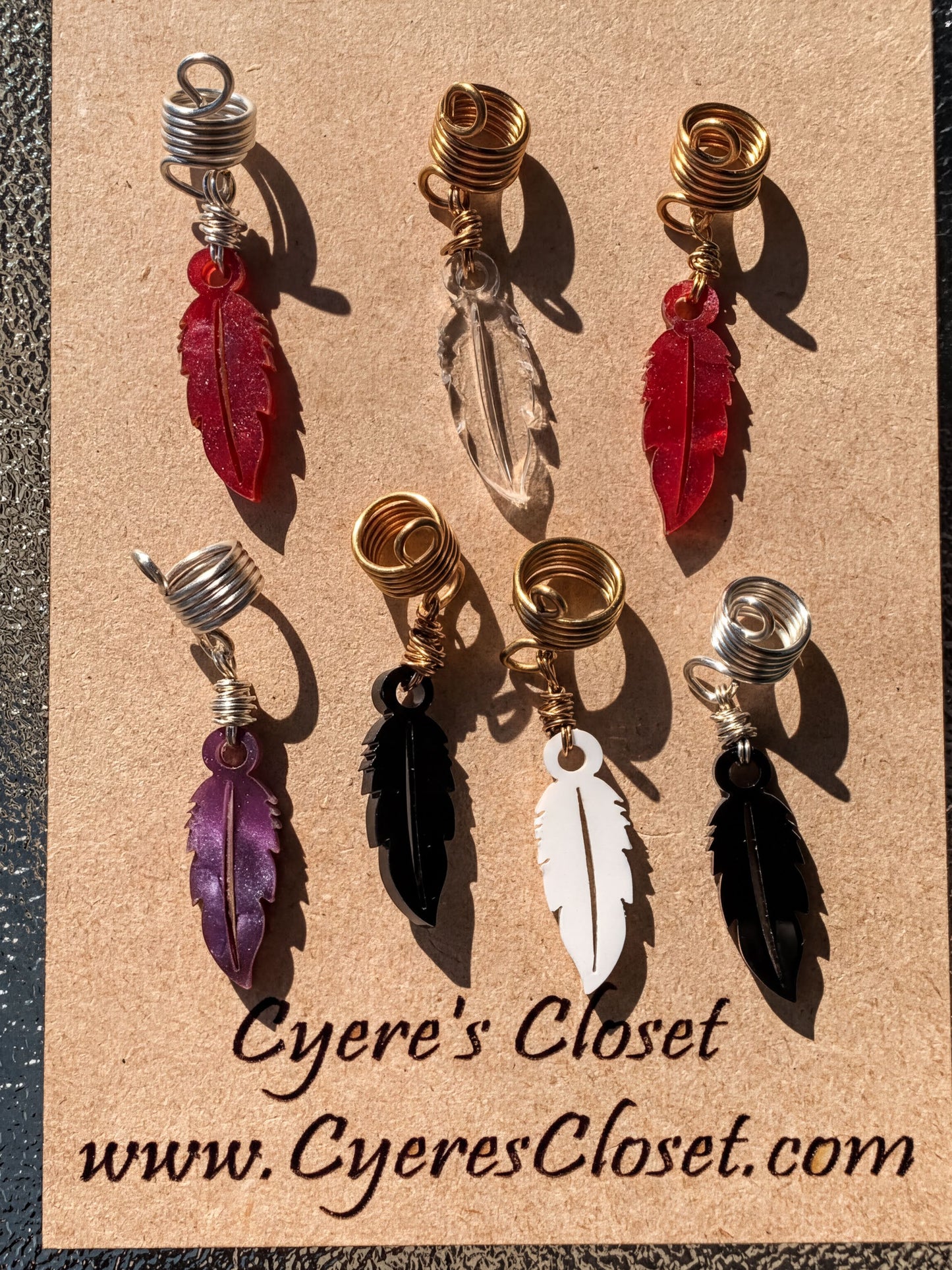 a collection of feather earrings with various colors and designs, including red, purple, black, and white feathers.