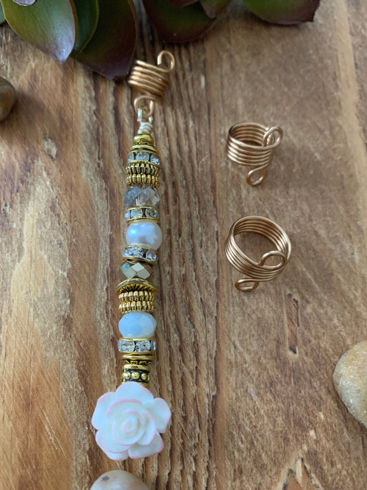 a wooden surface with a decorative hair accessory, including a hair clip and two gold spiral hair clips.