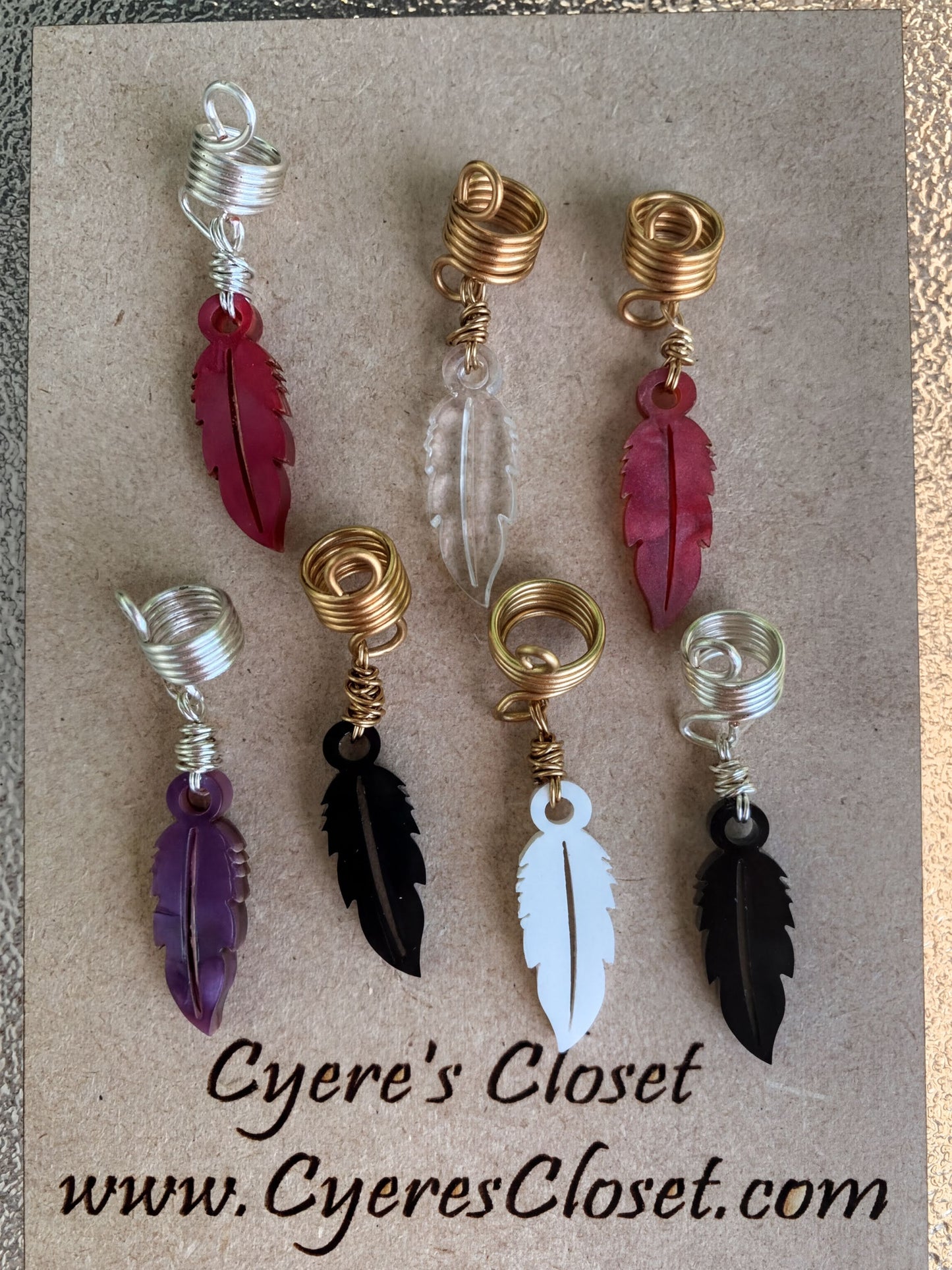 a collection of eight feather earrings, each with a unique color and design, arranged on a brown background.