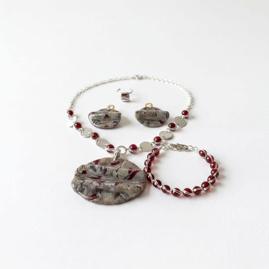 a collection of jewelry, including a necklace, earrings, and a bracelet, all featuring a combination of silver and red gemstones.