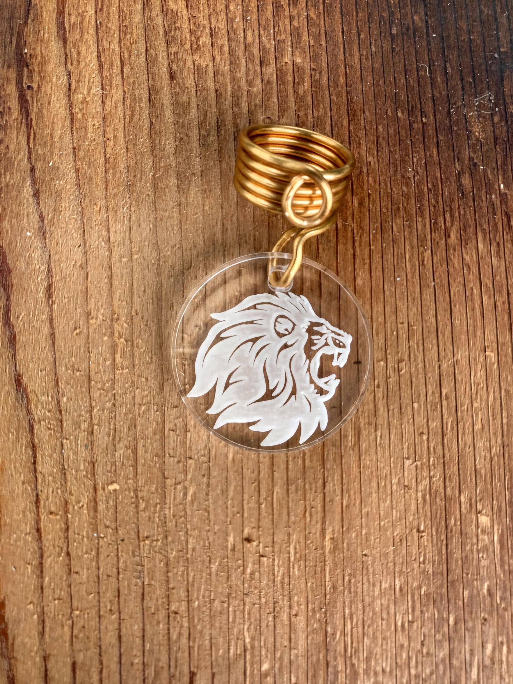 A clear plastic keychain with a gold ring attached, featuring a white lion's head design.