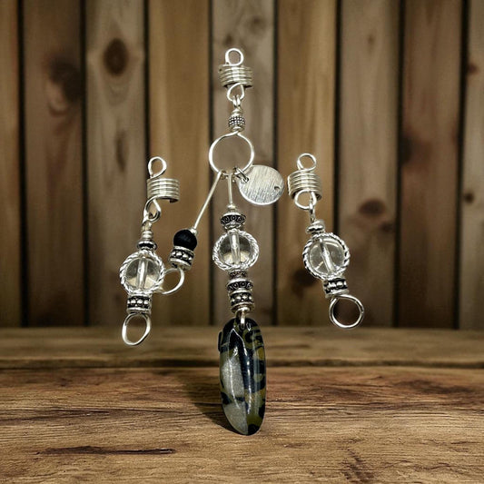 A collection of silver and glass jewelry pieces, including pendants and earrings, displayed on a wooden surface.