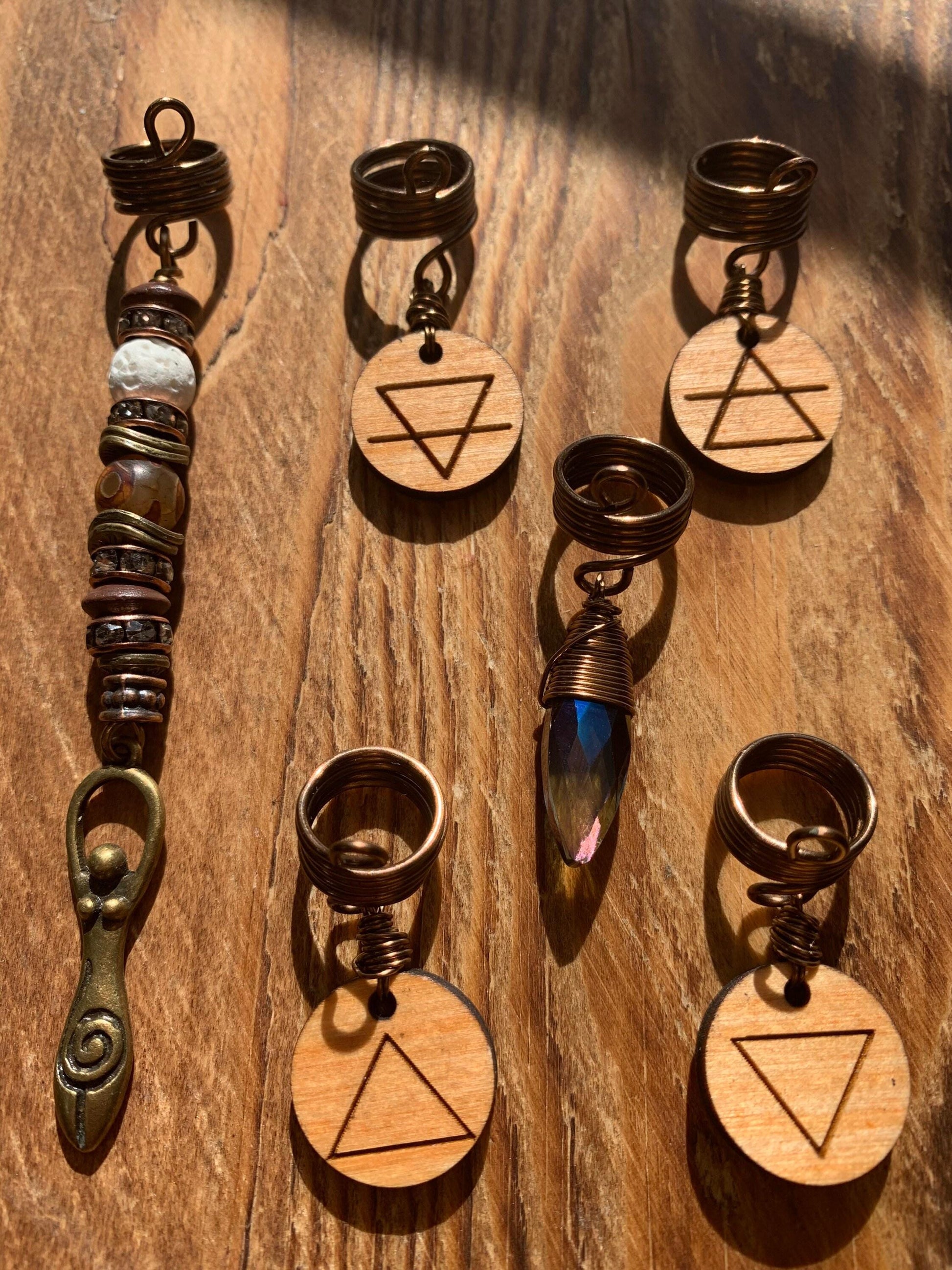 a collection of various wooden charms and pendants, each with unique designs and shapes, arranged on a wooden surface.