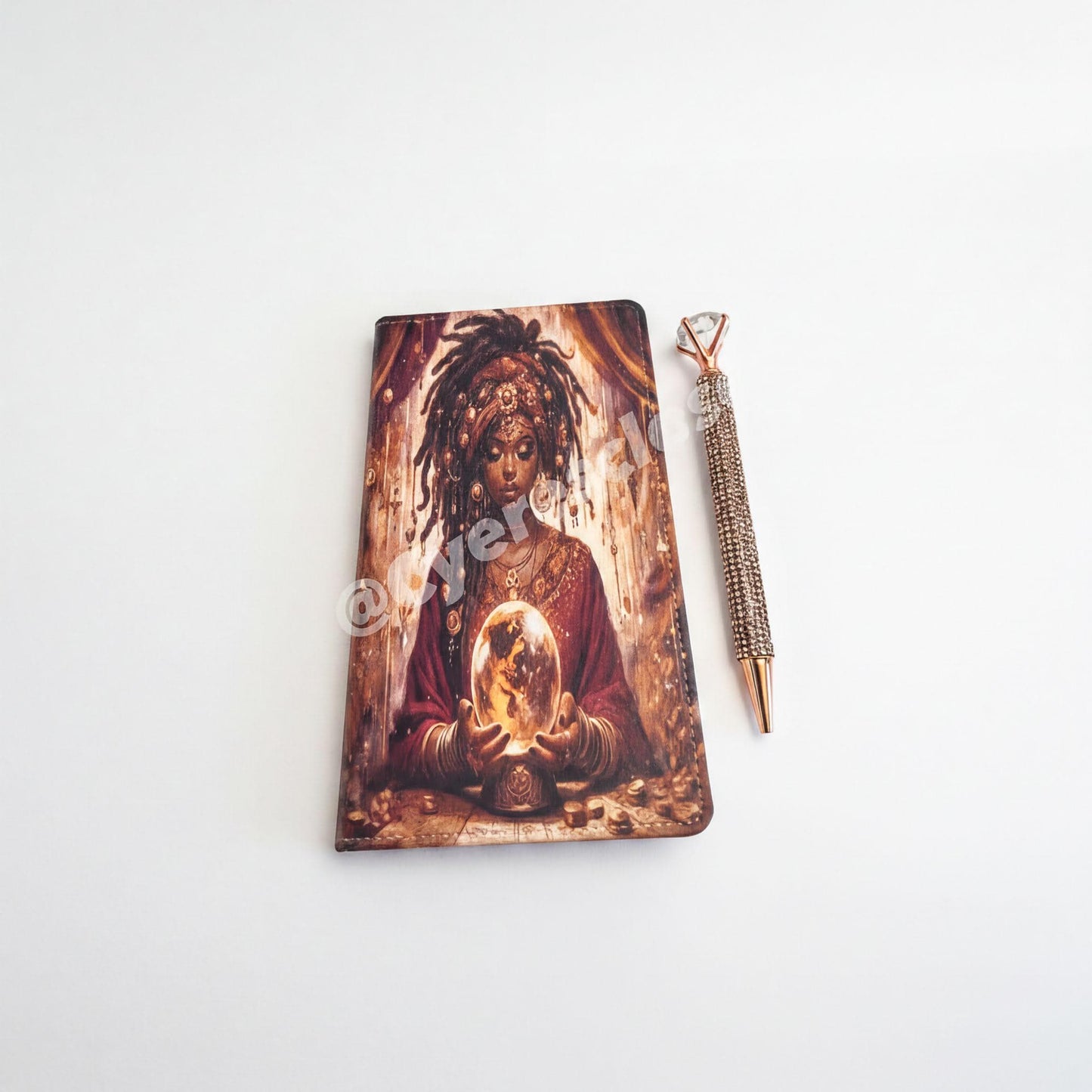 a notebook with an artistic illustration of a woman holding a crystal ball, accompanied by a pen.