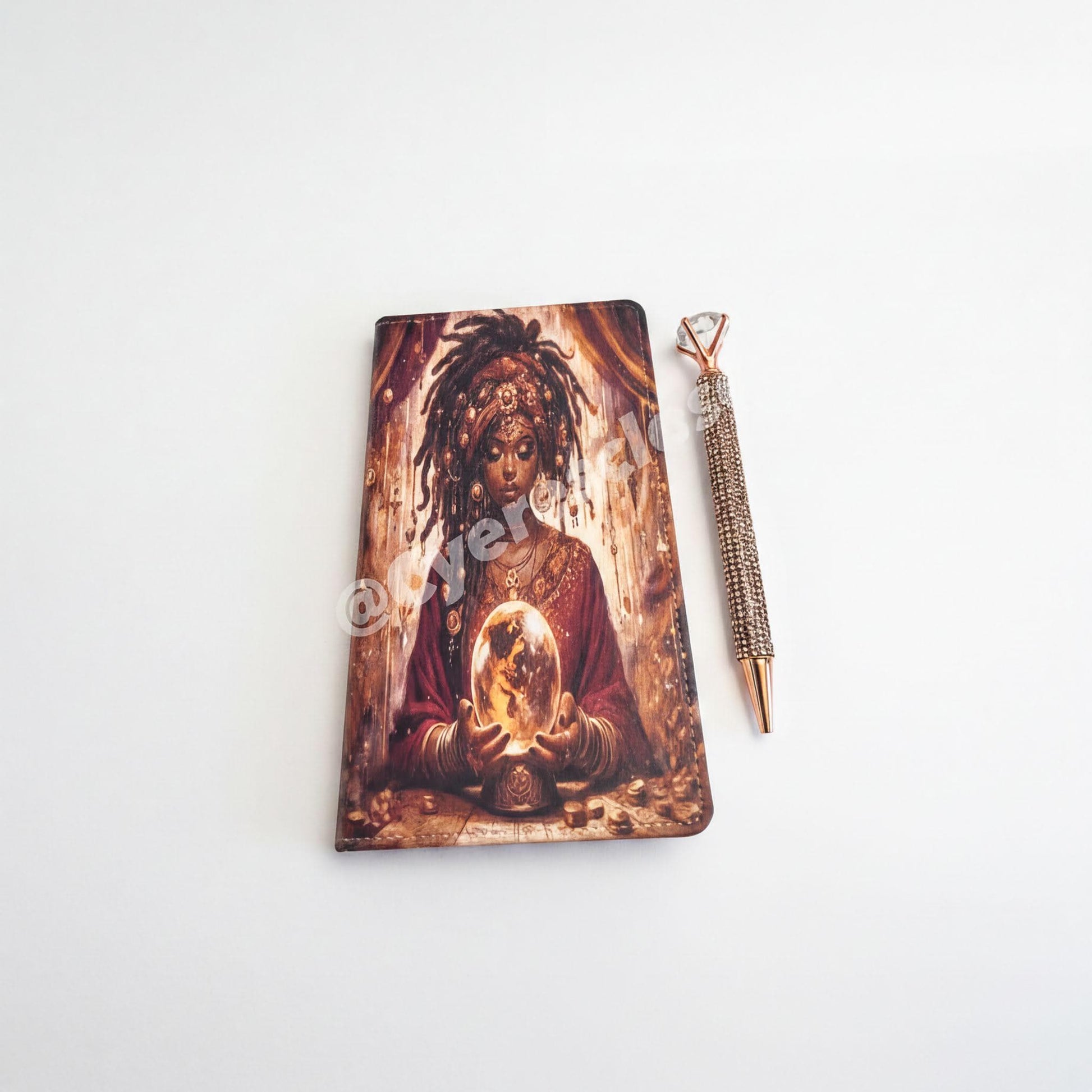 a notebook with an artistic illustration of a woman holding a crystal ball, accompanied by a pen.