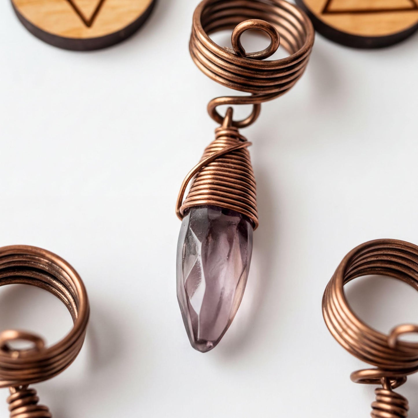 a close-up of a copper-colored pendant with a purple crystal, surrounded by other copper-colored pendants.