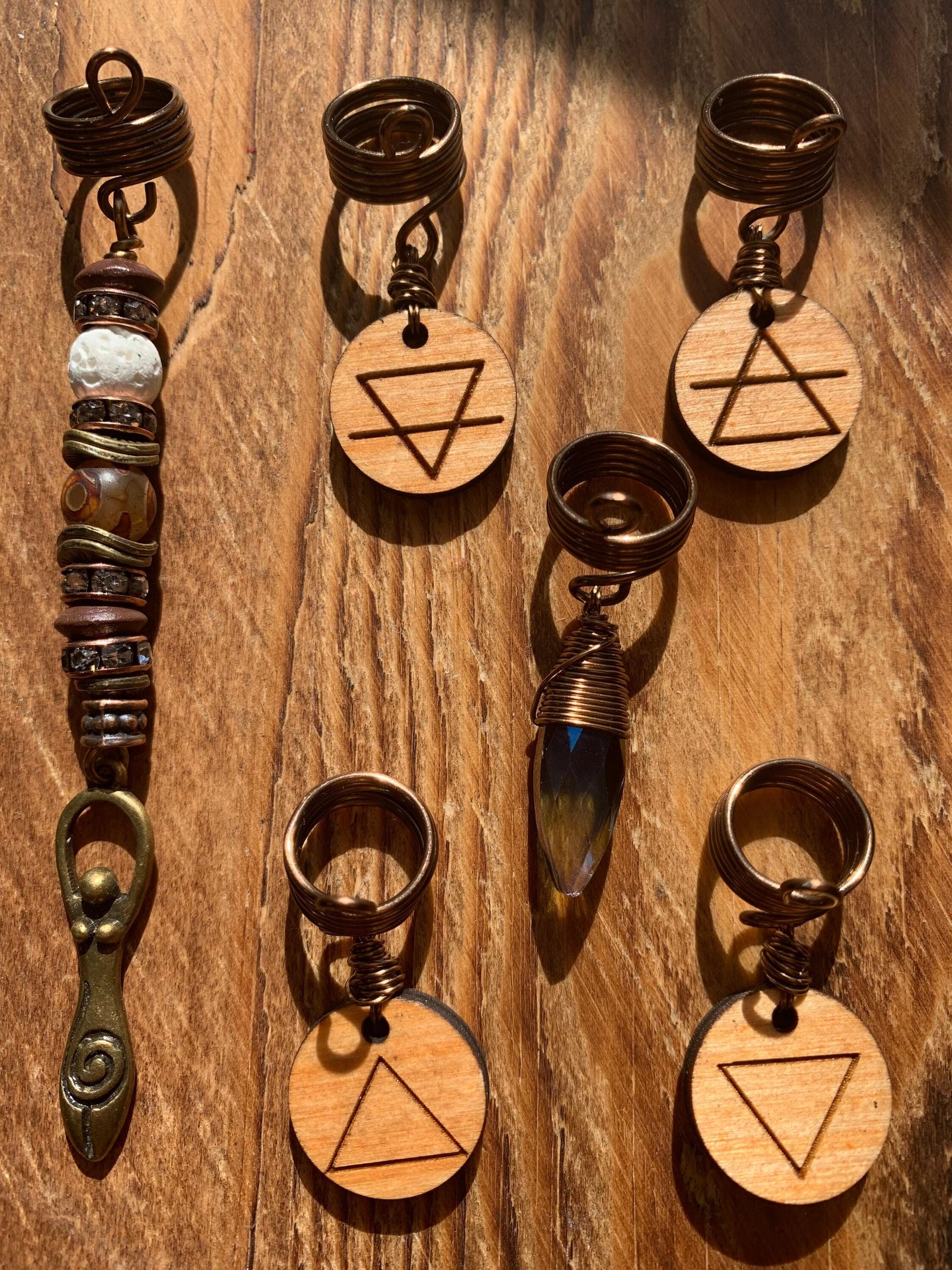 a collection of wooden pendants and charms, each with a unique design and shape, arranged on a wooden surface.