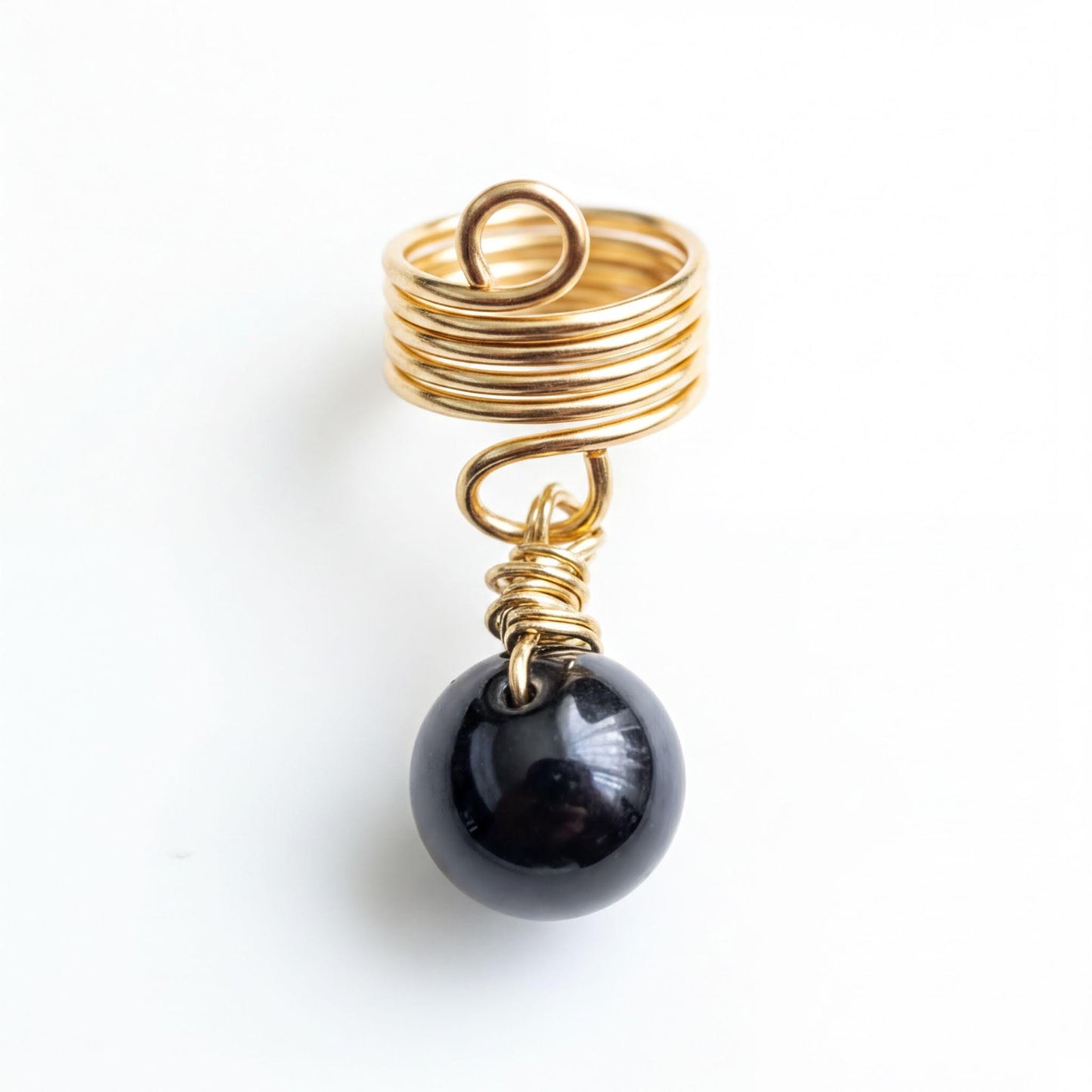 A gold ring with a spiral design and a black gemstone, possibly a pearl, hanging from it.