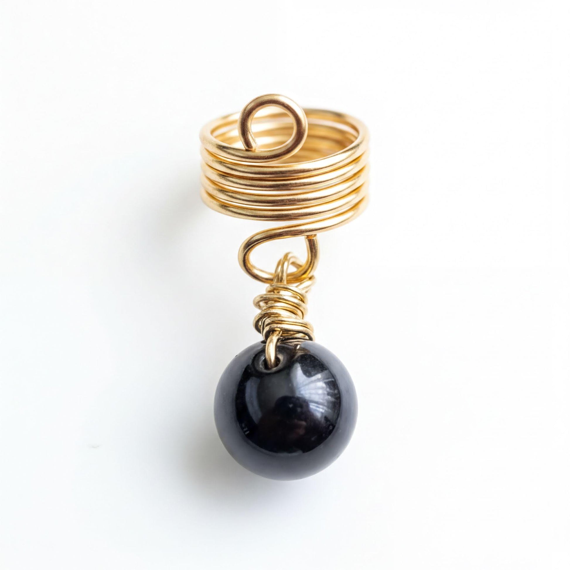 A gold ring with a spiral design and a black gemstone, possibly a pearl, hanging from it.