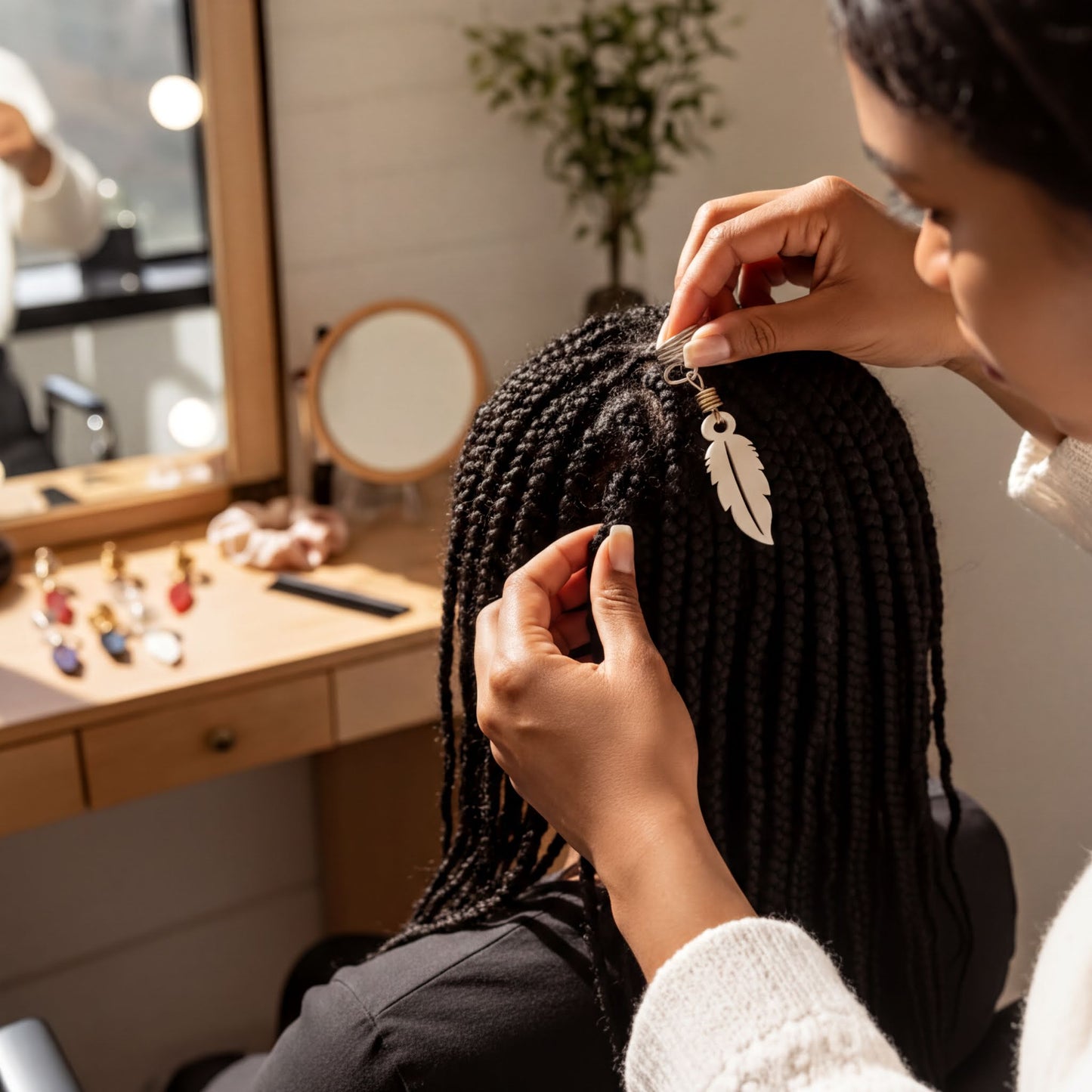 A person is styling a woman's braided hairstyle in a salon, with various hair products and tools visible on the counter.