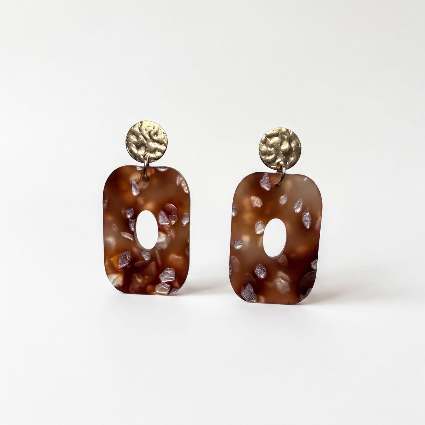 A pair of brown earrings with a textured surface and circular embellishments.