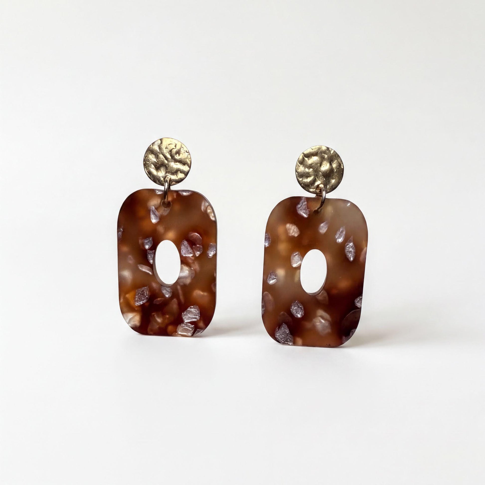 A pair of brown earrings with a textured surface and circular embellishments.