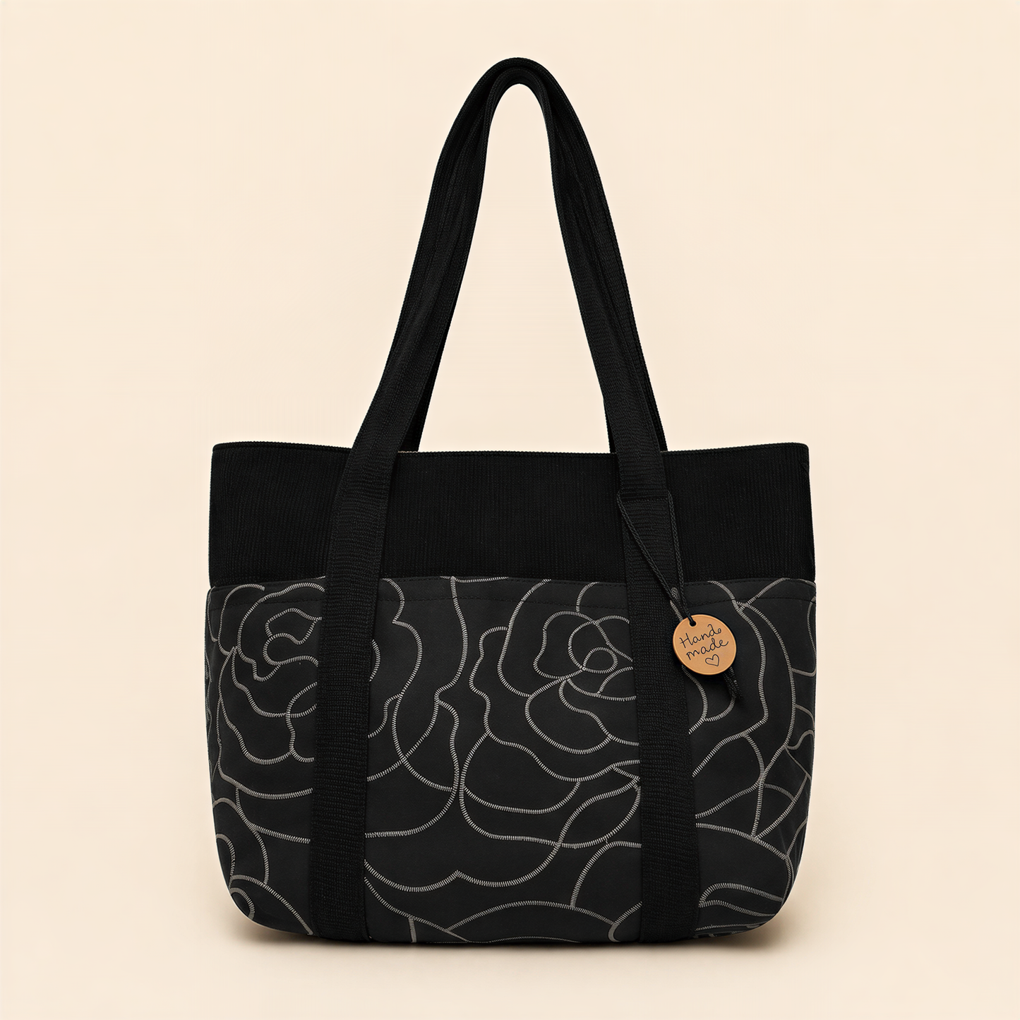 A black and gray floral patterned tote bag with a wooden tag attached.