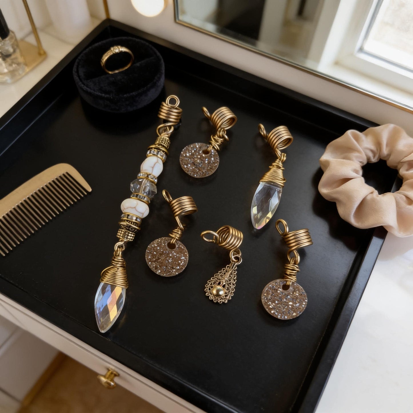 A collection of ornate jewelry and accessories, including a ring, earrings, and a hair tie, displayed on a black tray.
