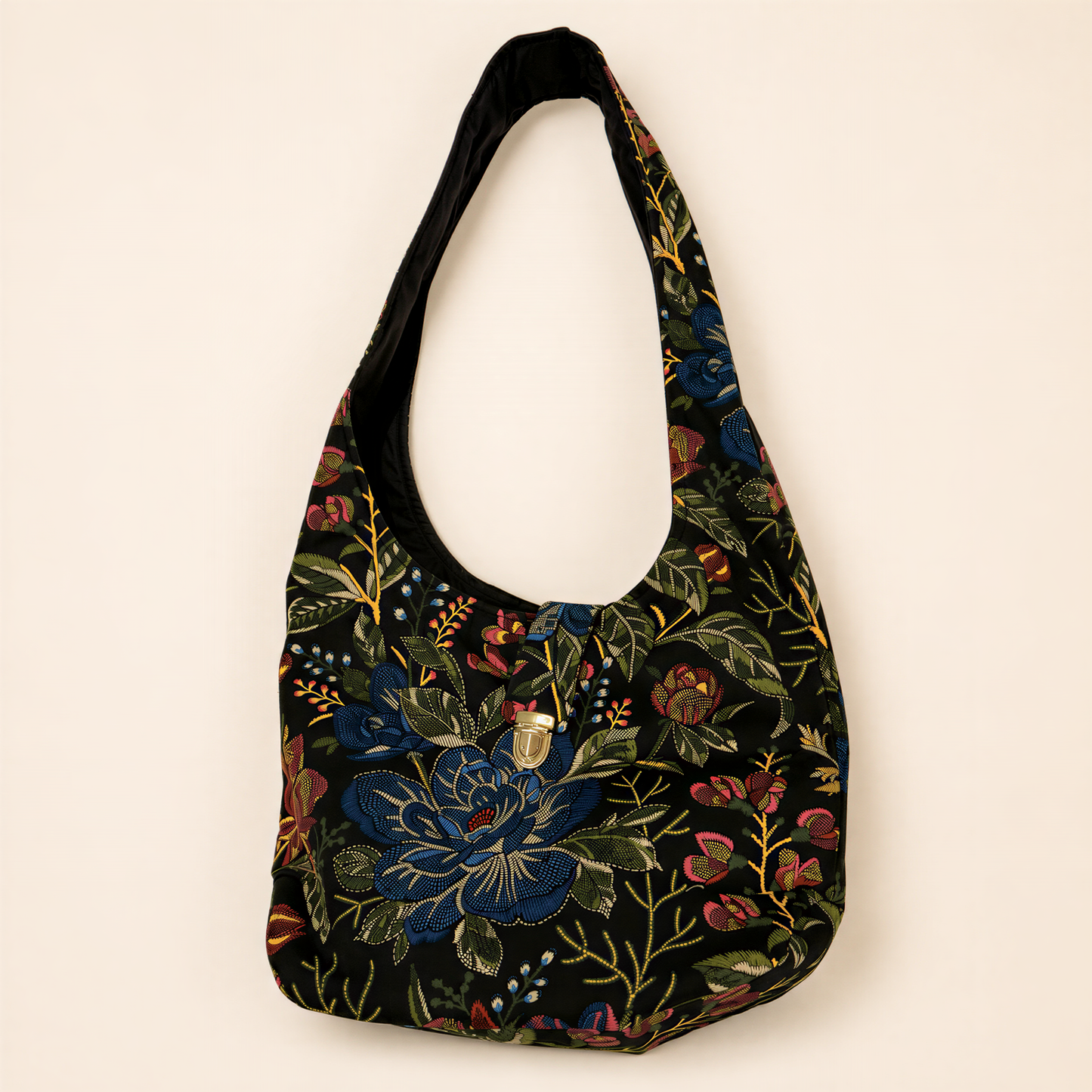 A black tote bag with a floral pattern on it, hanging against a plain background.