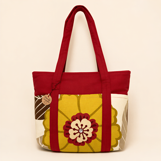 A red tote bag with a yellow and white floral pattern, featuring a large flower design in the center.