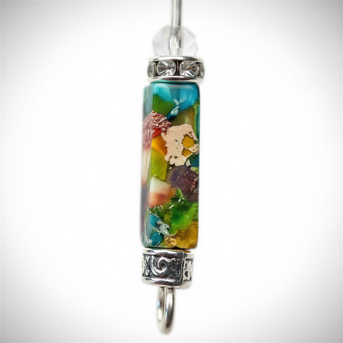 A colorful pendant with a clear gemstone at the top, hanging from a metal chain.