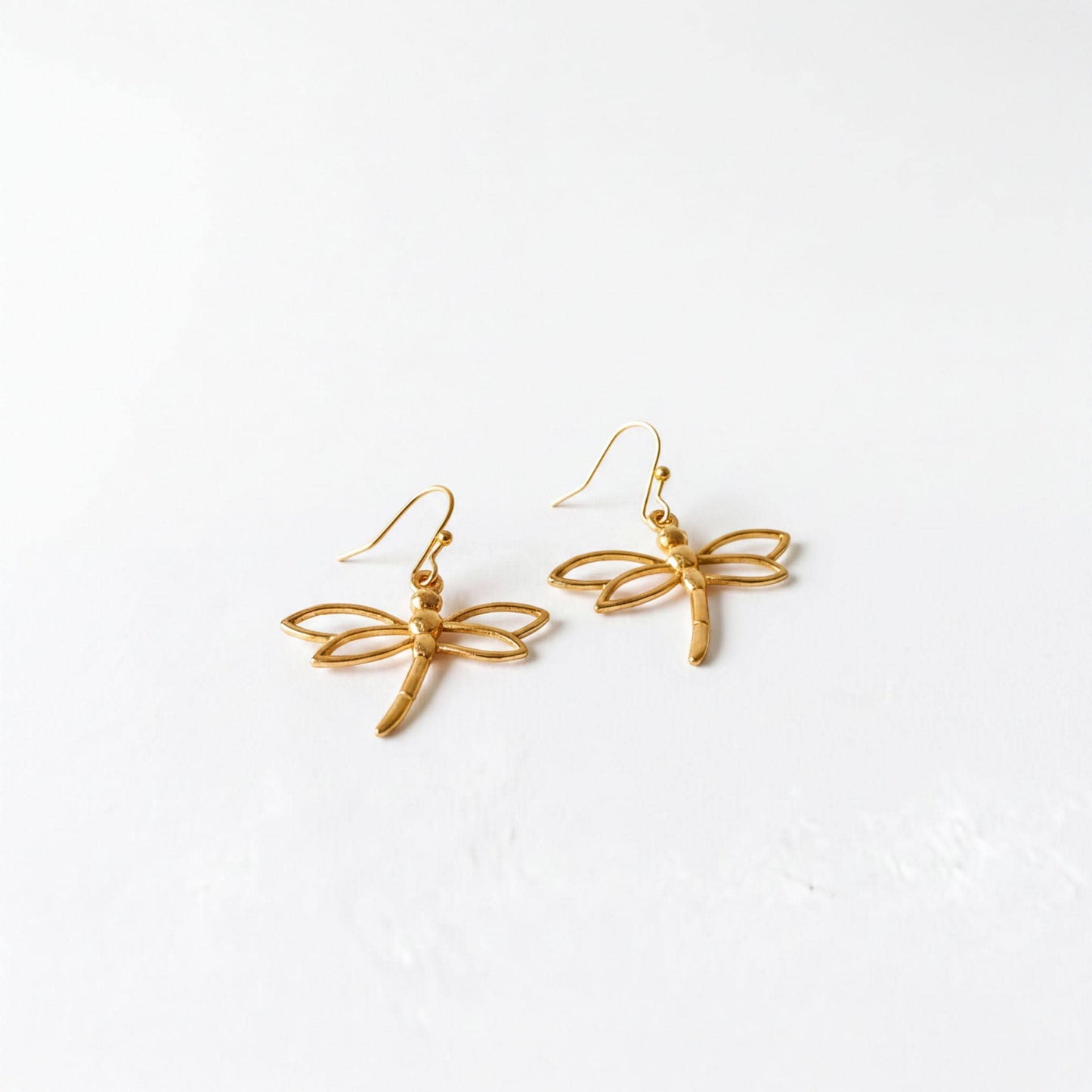 A pair of gold-colored earrings in the shape of a dragonfly.