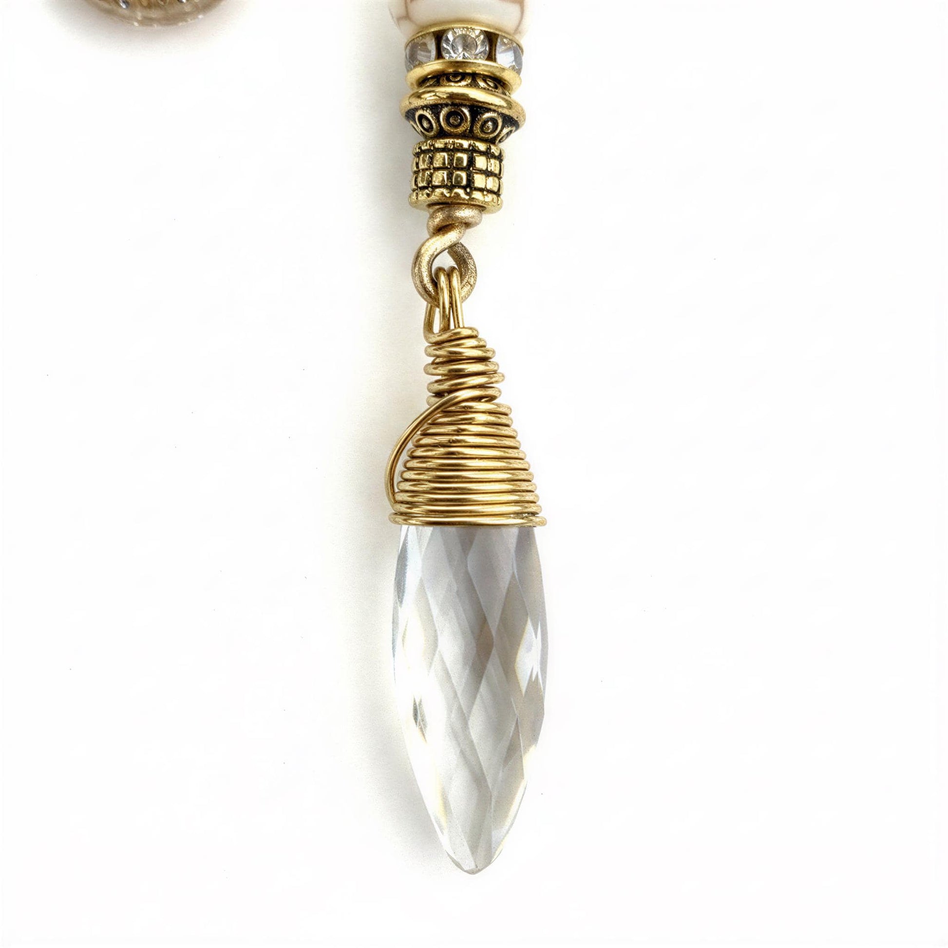 A close-up view of a clear crystal pendant with a twisted metal design, set against a white background.