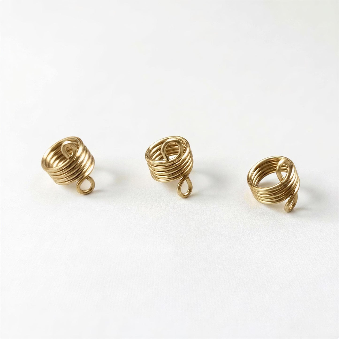 Three gold spiral rings are arranged in a row on a white background.