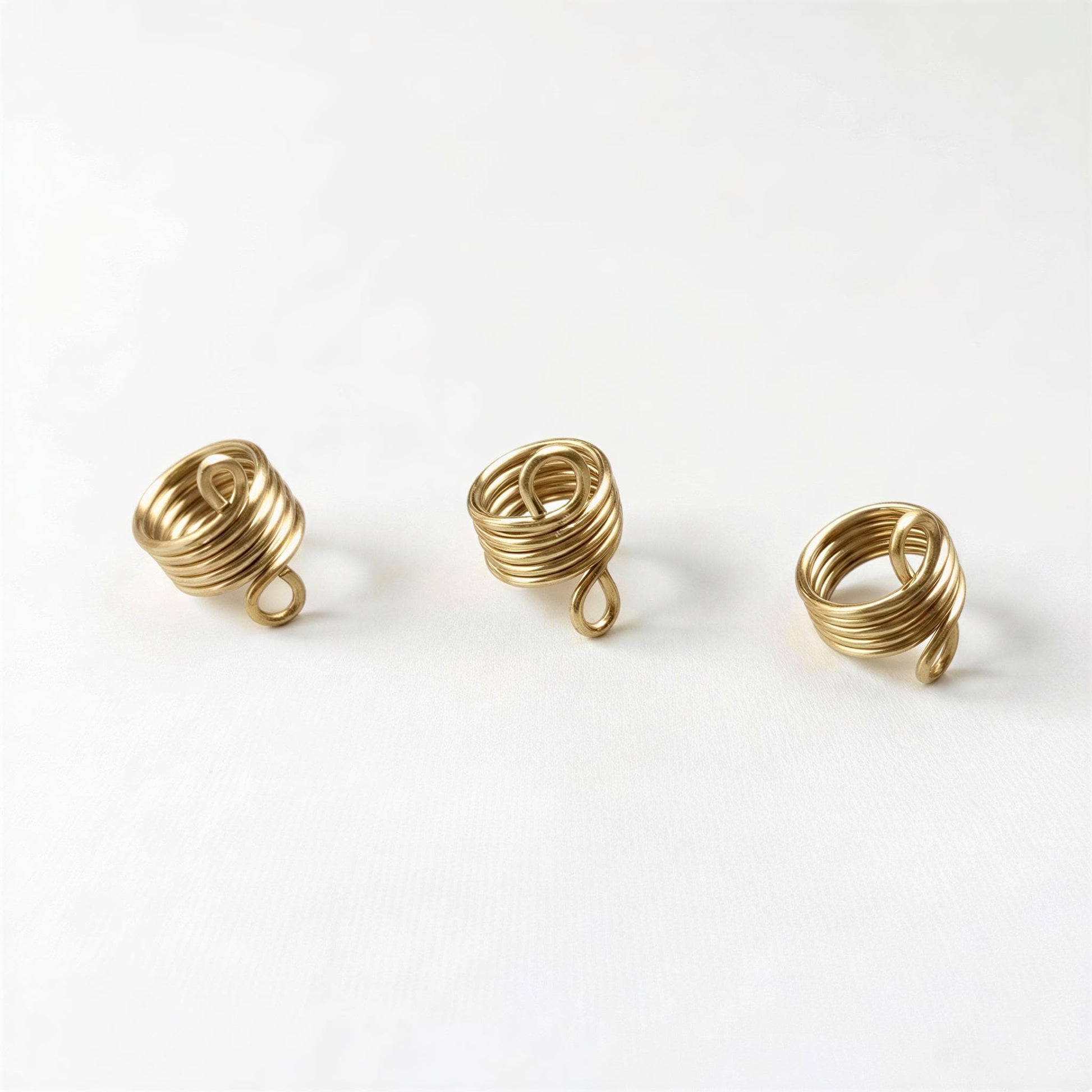Three gold spiral rings are arranged in a row on a white background.