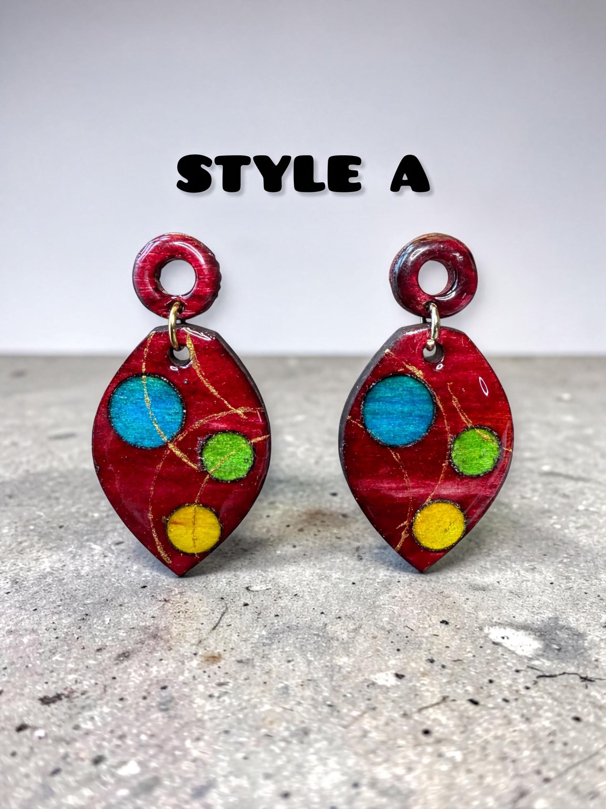 a pair of red earrings with colorful polka dots, displayed on a gray surface.