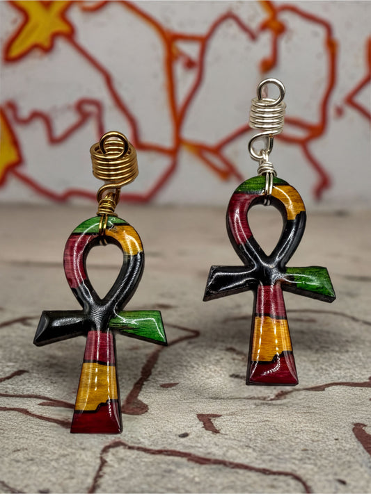 two colorful, abstract-shaped earrings with a cross-like design, placed on a textured surface against a graffiti-style background.