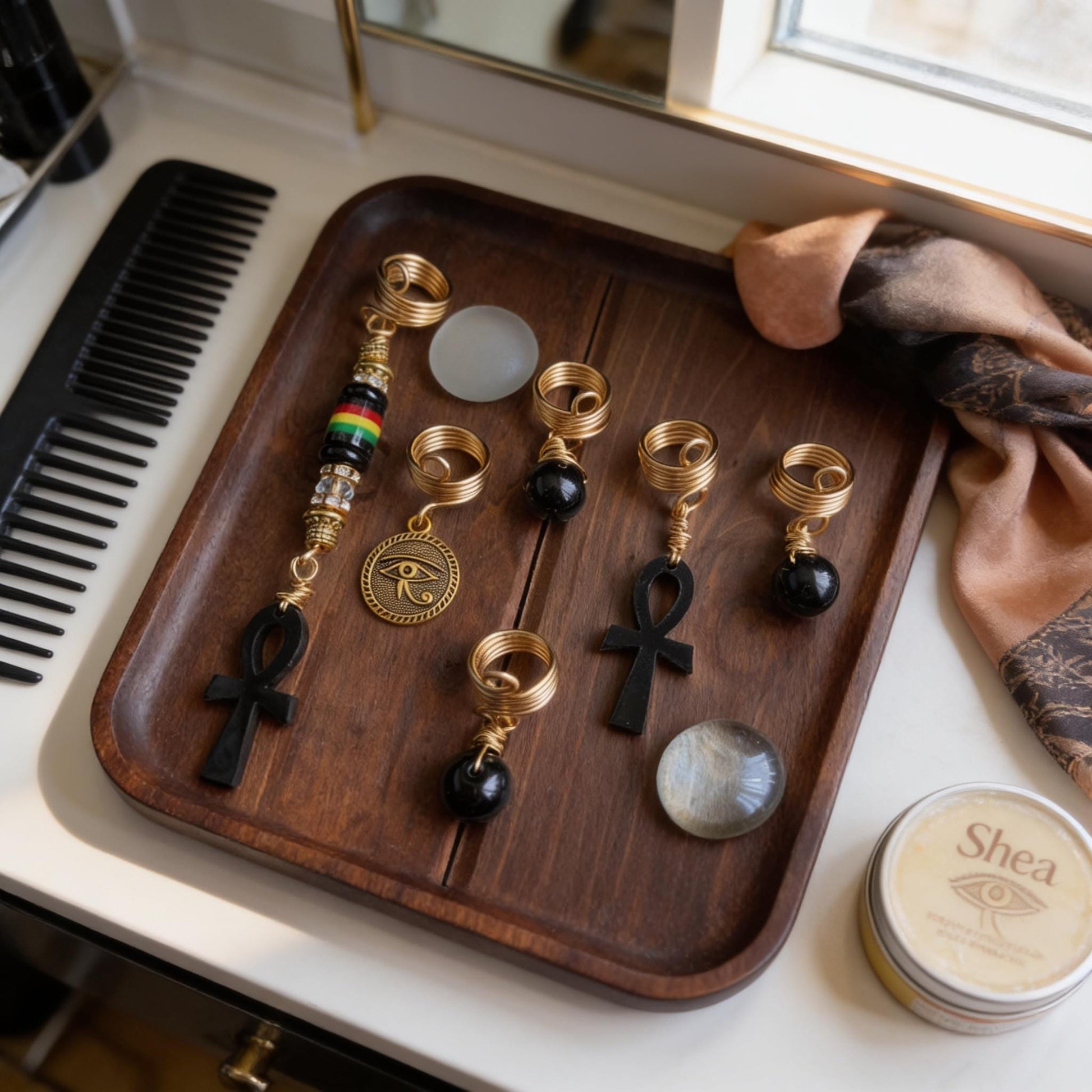 A wooden tray displaying various jewelry pieces, including a cross, on a white countertop.