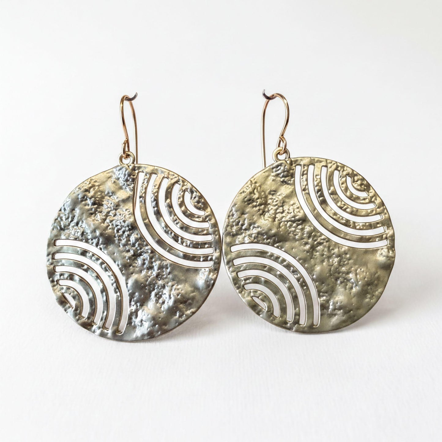 two round earrings with a metallic texture and a repeating wave pattern design.