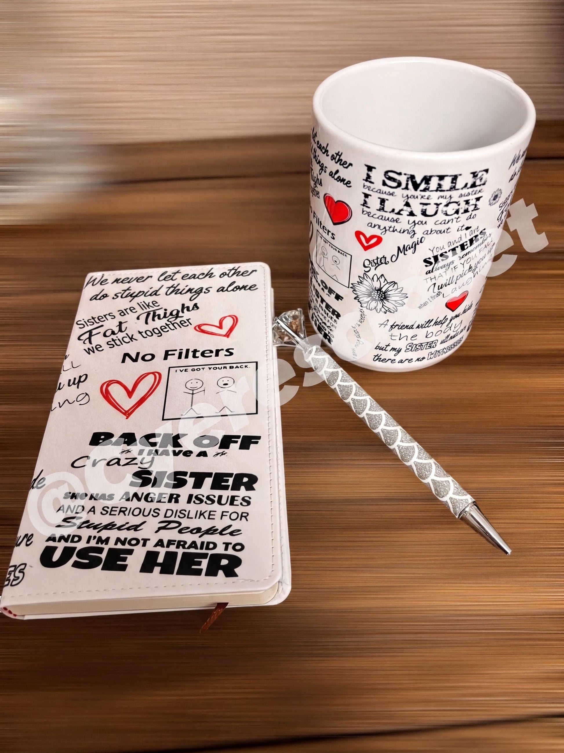 A mug with a printed design, a notebook with a printed design, and a pen on a wooden surface.