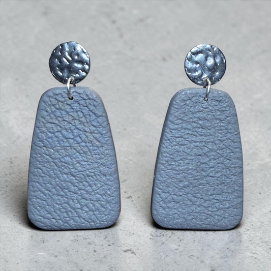 A pair of gray, textured earrings with metal circular elements on top.