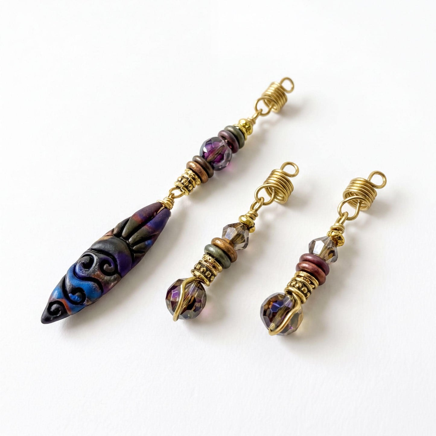 three decorative earrings with colorful beads and twisted metal elements.