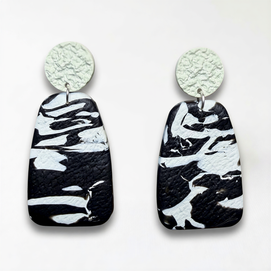 A pair of black and white marble-patterned earrings with a textured finish.