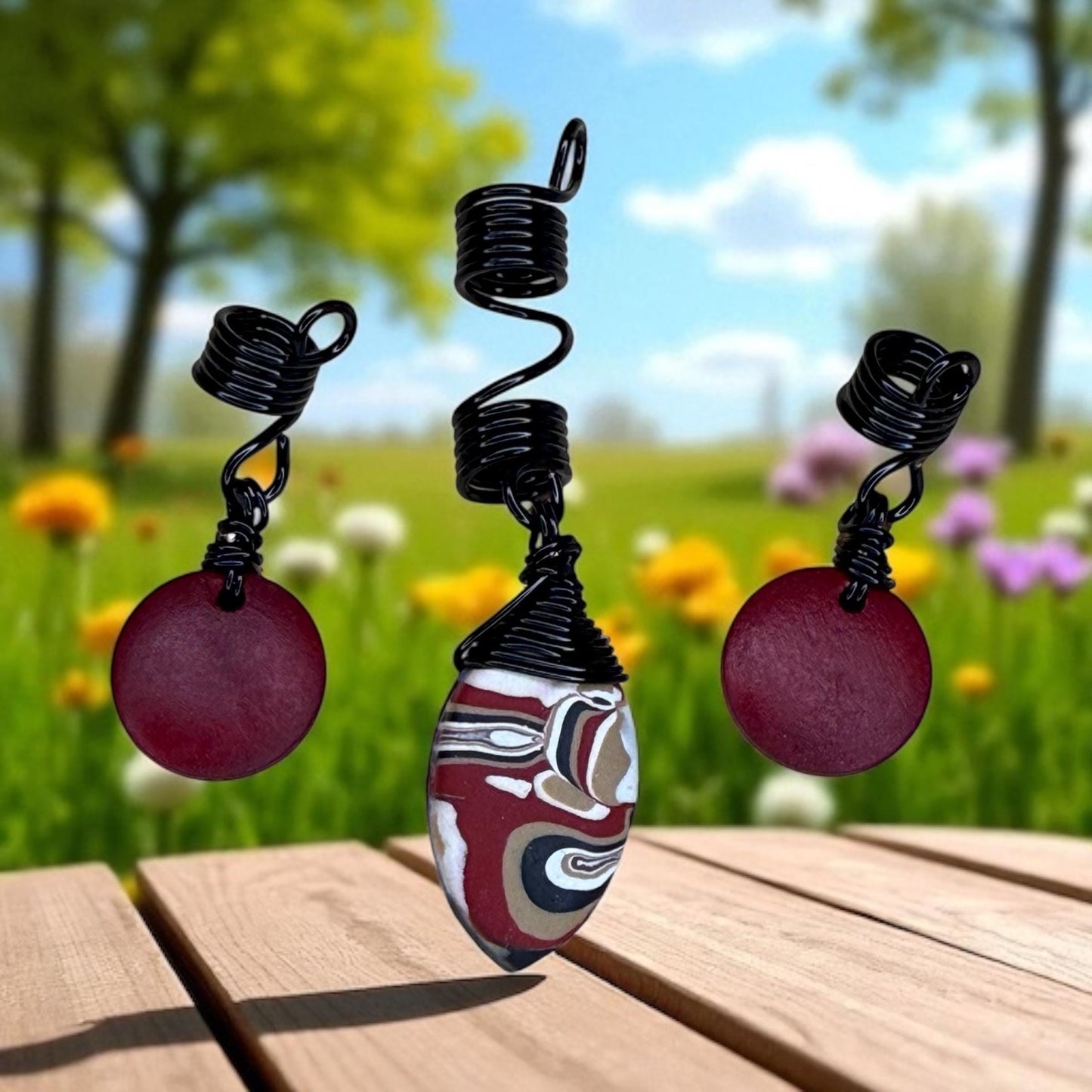 A pair of earrings with spiral coiled designs and round pendants, set against a blurred background of a grassy field with trees and flowers.