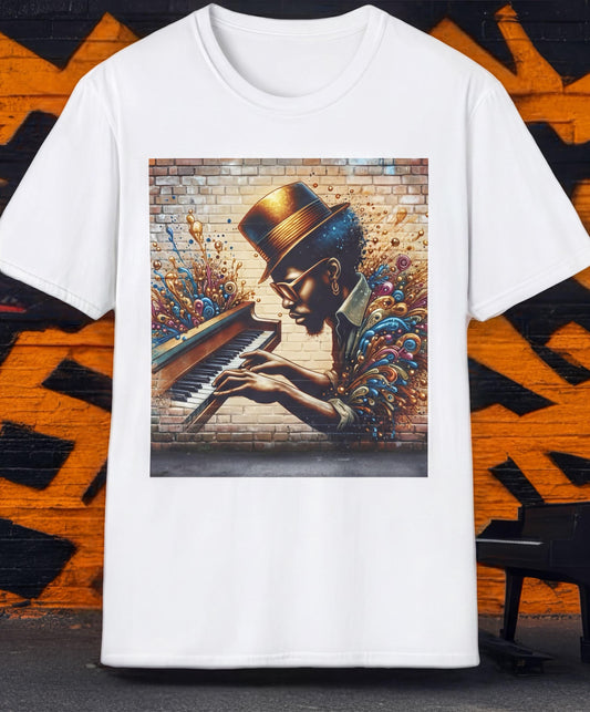 A white t-shirt with a colorful graphic design depicting a person playing a piano against a brick wall background.