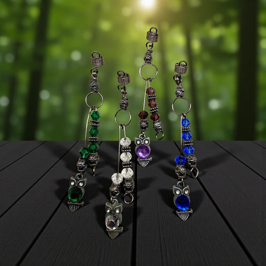 A collection of ornate owl-shaped earrings with various colored beads and charms, displayed on a wooden surface against a blurred green background.