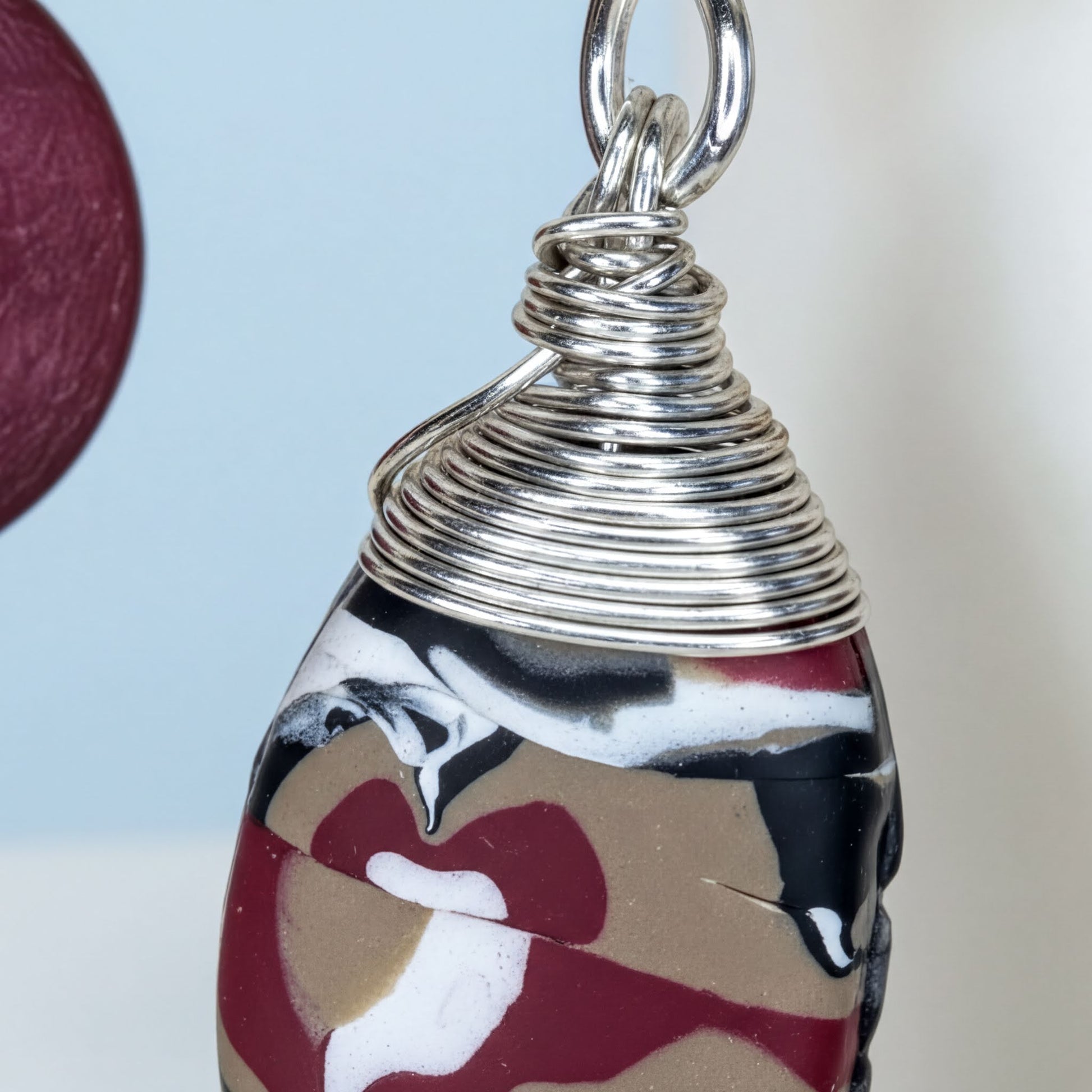 A close-up image of a pendant with a twisted metal wire and a colorful, abstract design.