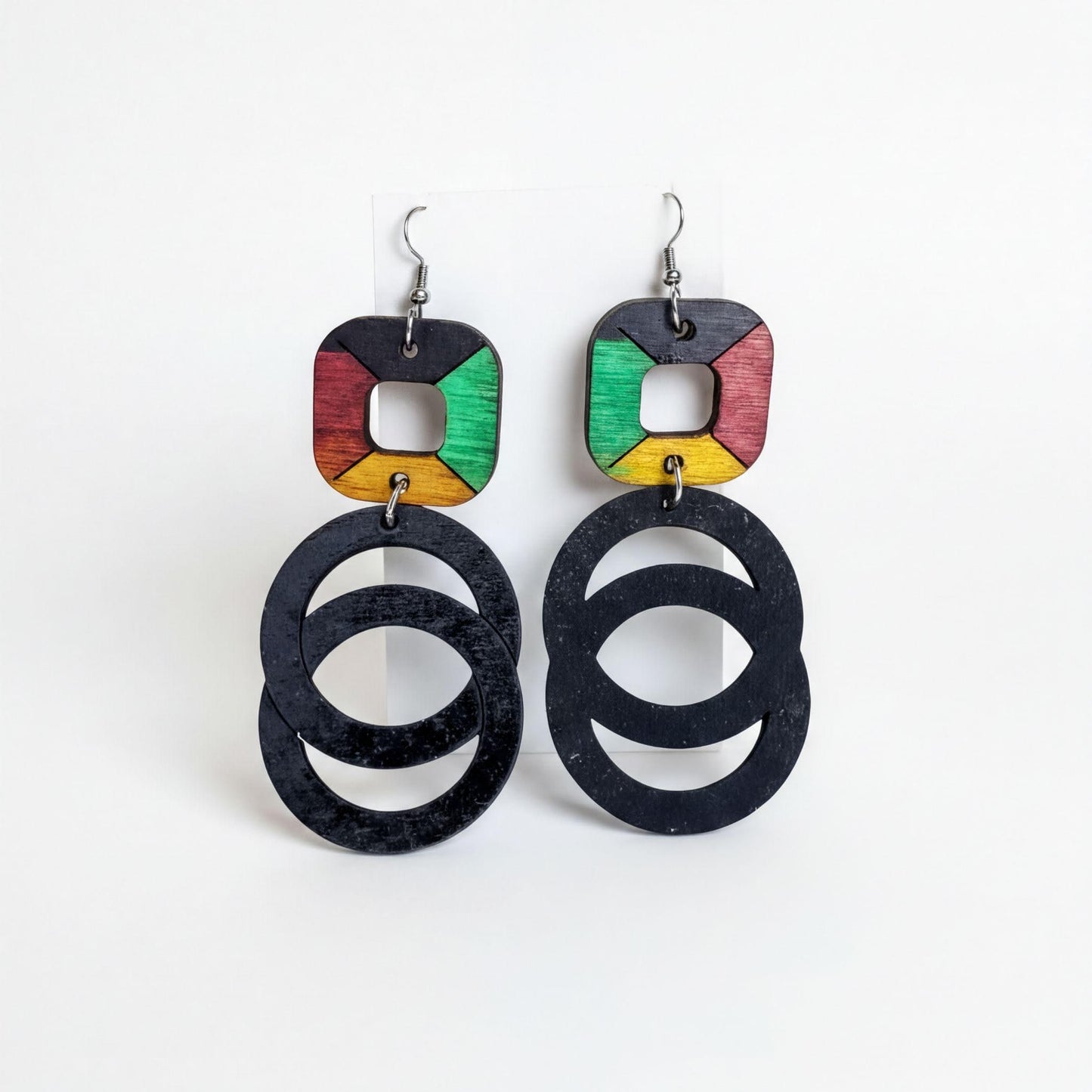 A pair of earrings with a unique design, featuring a combination of black, green, and yellow circular shapes.