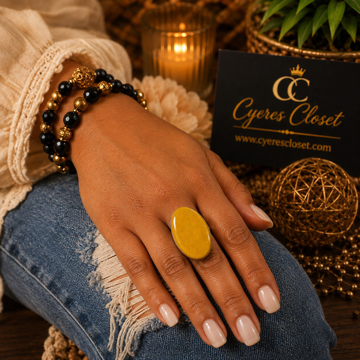 Cyere's Closet mustard yellow hand-painted oval basswood statement ring worn on a hand with beaded bracelets