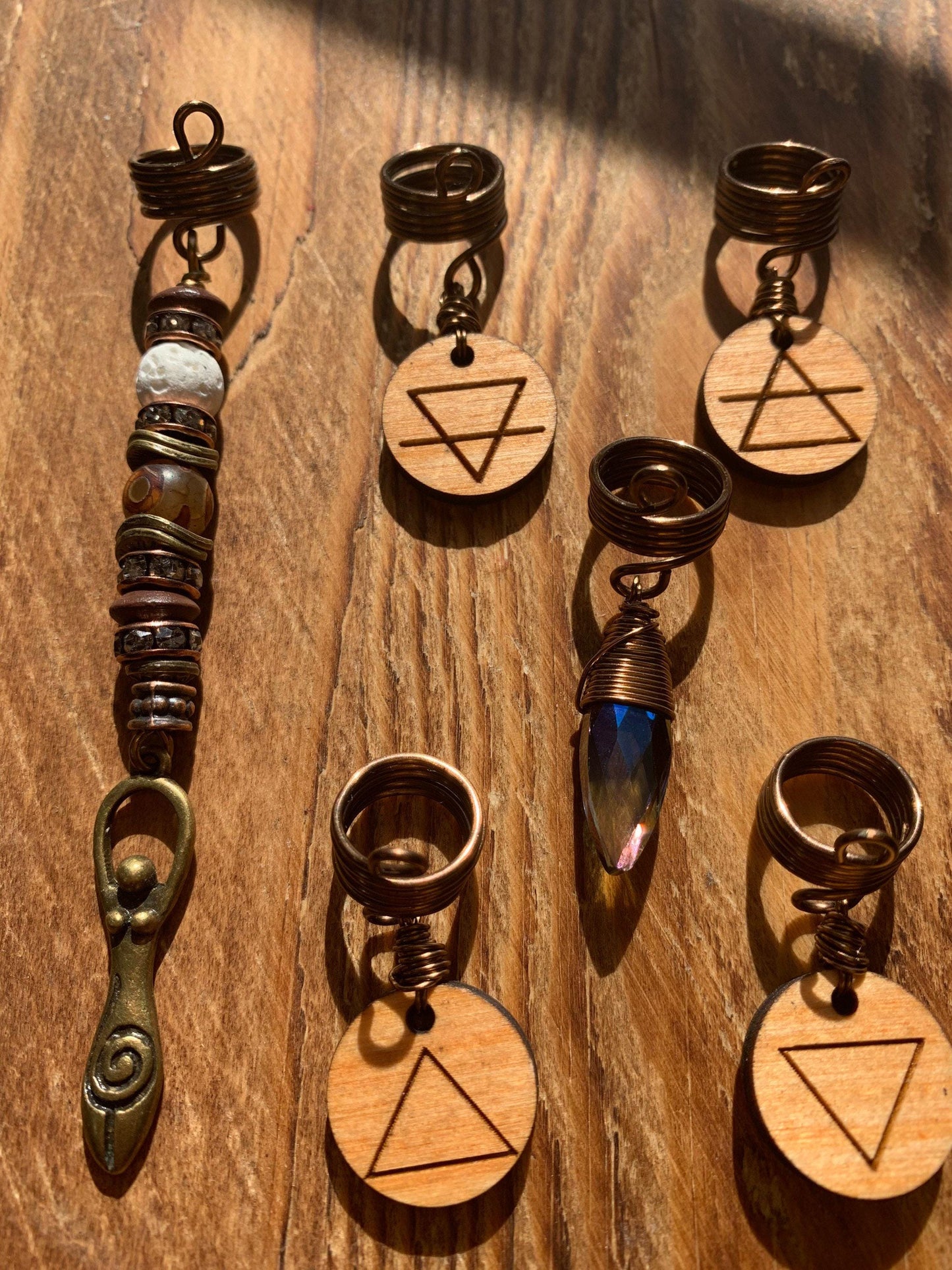 a collection of wooden charms and pendants, each with a unique design and shape, arranged on a wooden surface.