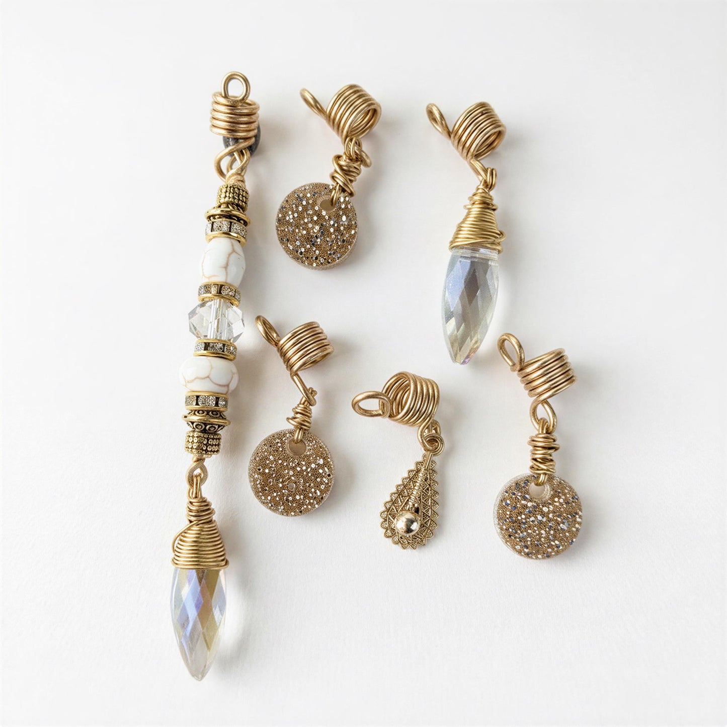 a collection of six gold-colored jewelry pieces, including earrings and pendants, arranged on a white background.