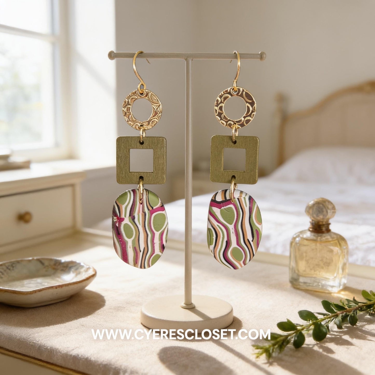a pair of earrings displayed on a stand, with a small bowl and a bottle of perfume placed nearby.