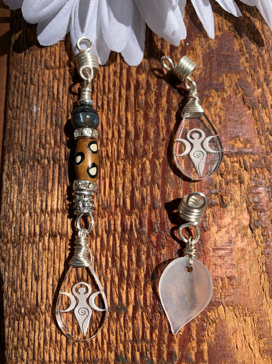 a collection of three unique earrings, each with distinct designs and materials. The earrings are suspended from a wooden surface, creating an interesting visual effect.