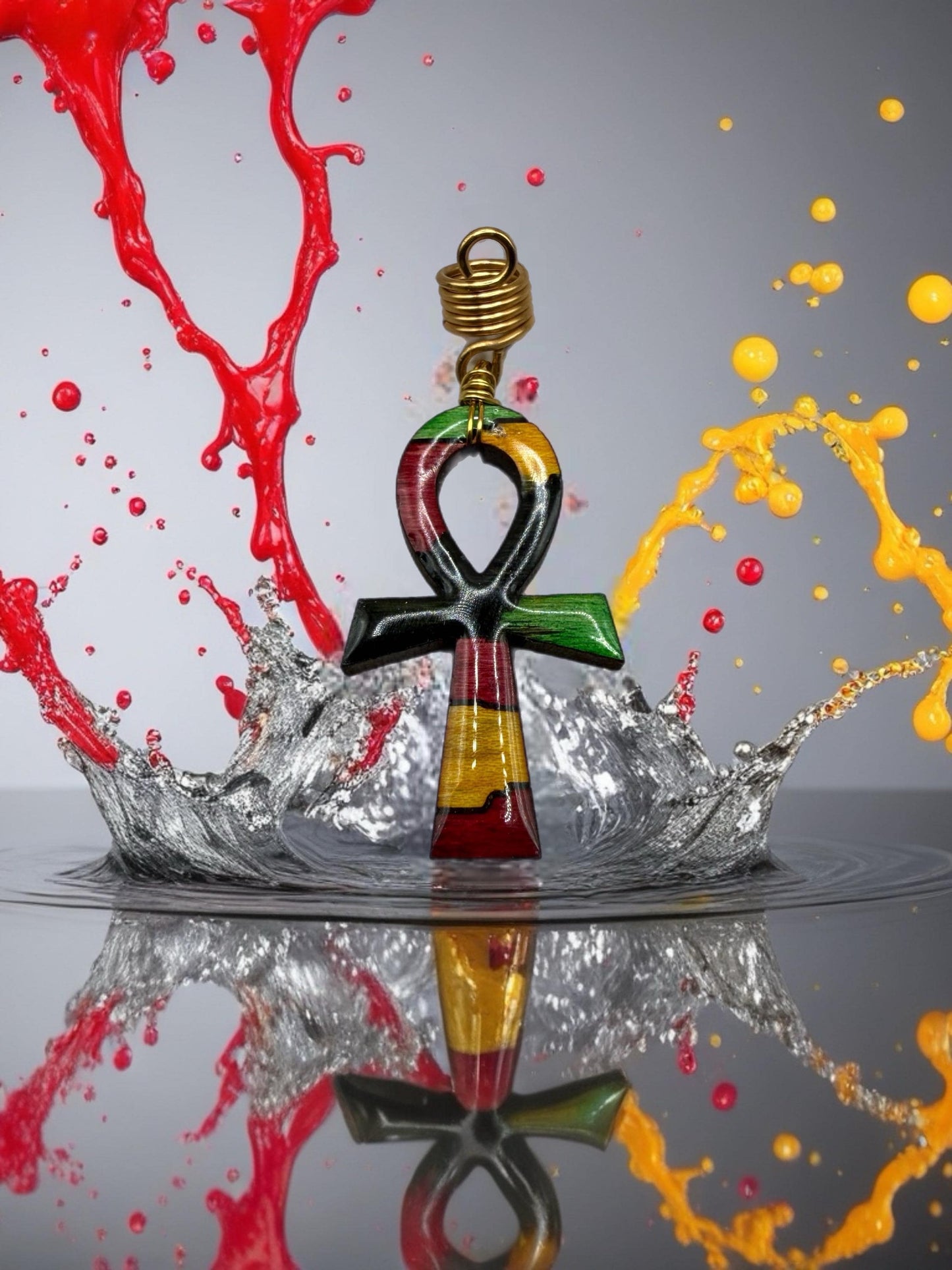 a colorful pendant with an Ankh symbol, surrounded by splashes of red and yellow paint, creating a vibrant and dynamic composition.